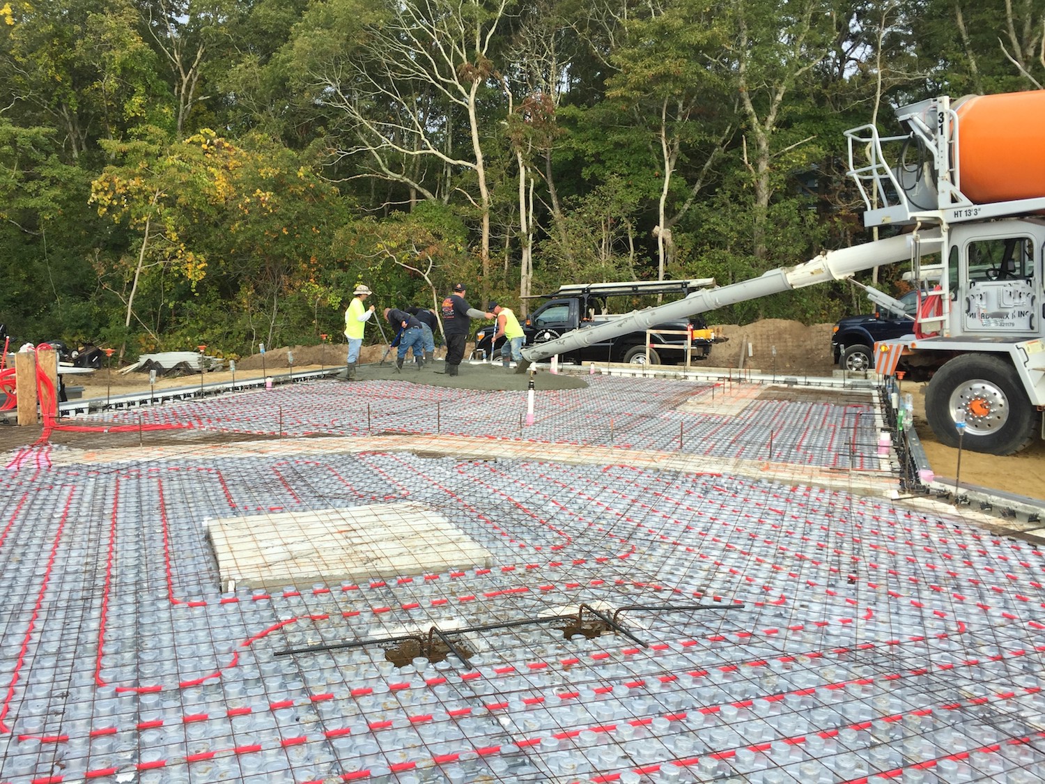 Concrete is poured onto the ground floor of a new ICF construction house with Radiant heating visible in the gridwork of the floor.