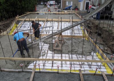 A team of workers laying out the concrete as it is poured in the base layer of a new pool that will be built with ICF forms.