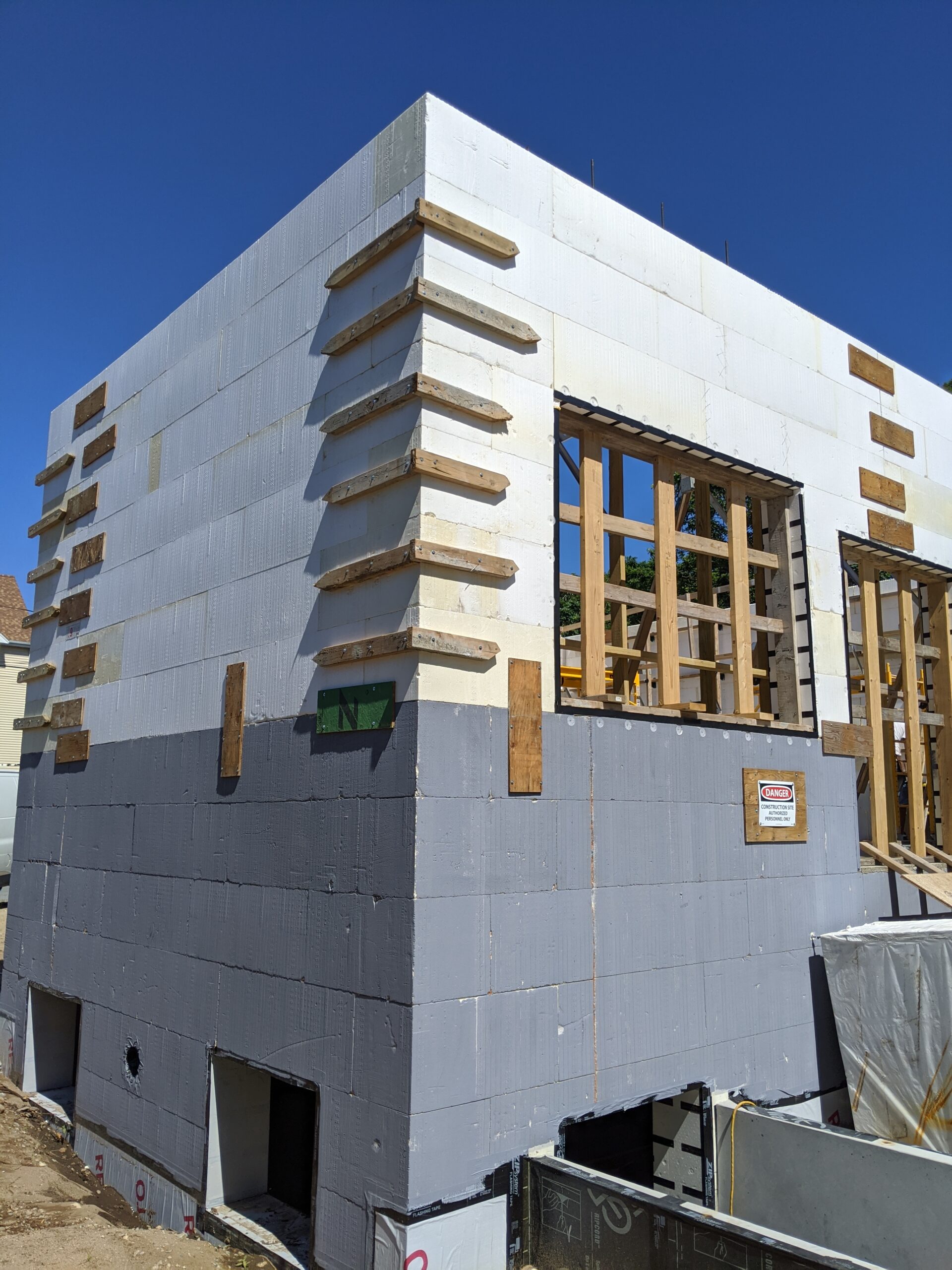 Corner view of ICF Building with an ICF Foundation and first floor secured. Image shows waterproofing at the base of the ICF Foundation of the building and a cast in place basement entrance attached to the foundation